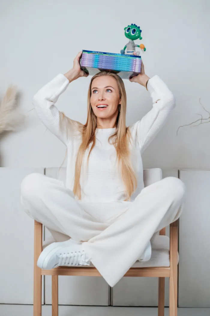 Rašytoja Jovita Mazina sėdi su knygomis ant galvos